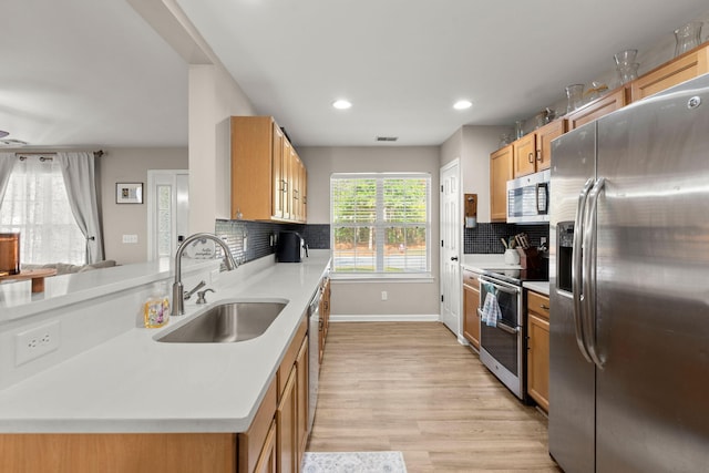 kitchen featuring light hardwood / wood-style floors, sink, appliances with stainless steel finishes, and tasteful backsplash