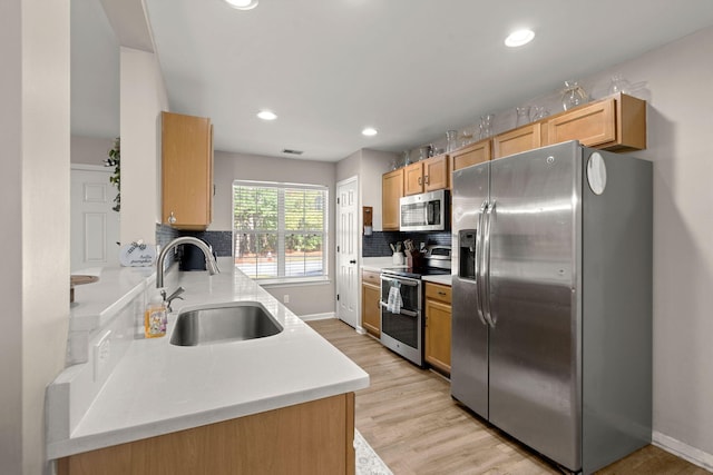 kitchen featuring sink, tasteful backsplash, light wood-type flooring, light brown cabinetry, and appliances with stainless steel finishes