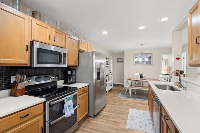 kitchen with pendant lighting, sink, light hardwood / wood-style flooring, tasteful backsplash, and stainless steel appliances