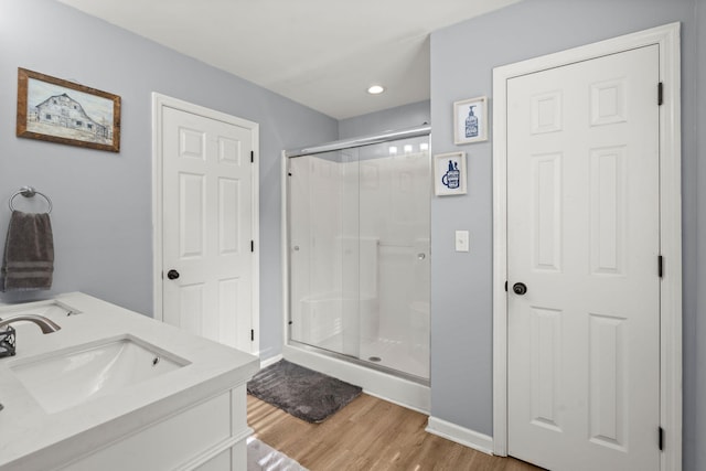 bathroom featuring hardwood / wood-style flooring, vanity, and a shower with door