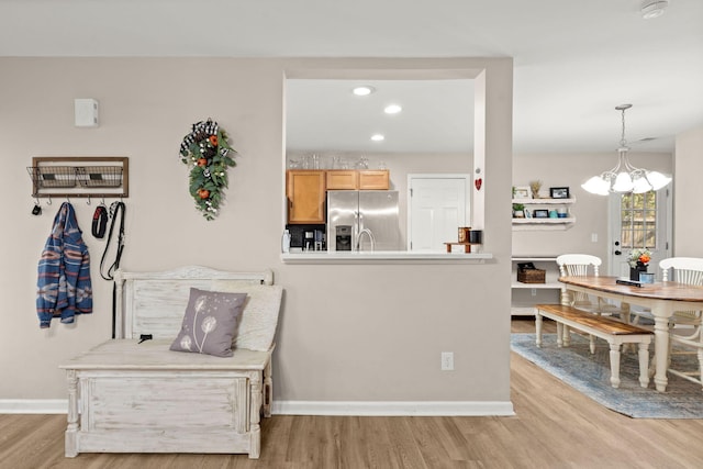 kitchen with stainless steel refrigerator with ice dispenser, decorative light fixtures, light hardwood / wood-style flooring, and a notable chandelier