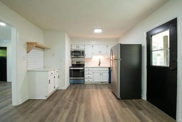 kitchen with dark wood-type flooring, white cabinets, sink, tasteful backsplash, and stainless steel appliances