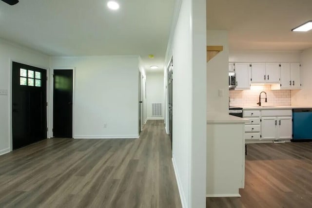 interior space featuring backsplash, black appliances, sink, hardwood / wood-style flooring, and white cabinetry