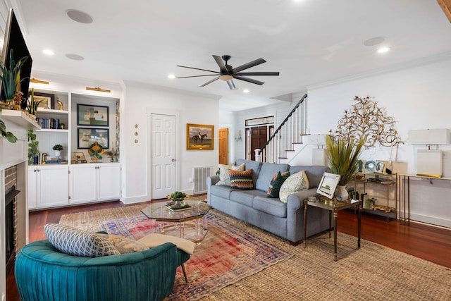 living room with a fireplace, hardwood / wood-style flooring, ceiling fan, and ornamental molding