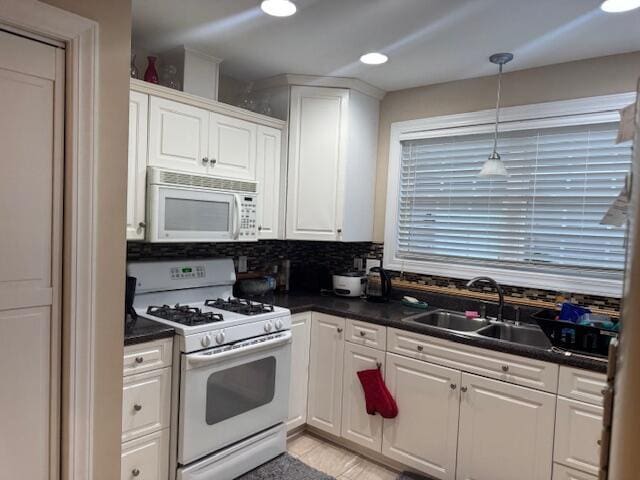 kitchen with tasteful backsplash, white appliances, sink, decorative light fixtures, and white cabinets