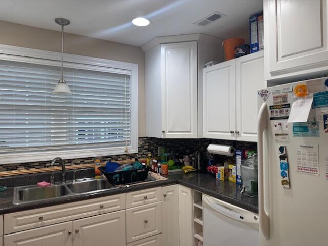 kitchen featuring decorative backsplash, white appliances, white cabinetry, and sink