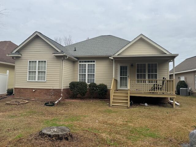 rear view of house with covered porch, a yard, and cooling unit