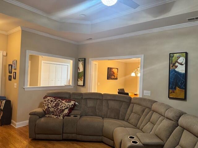 living room featuring a chandelier, hardwood / wood-style floors, a raised ceiling, and ornamental molding