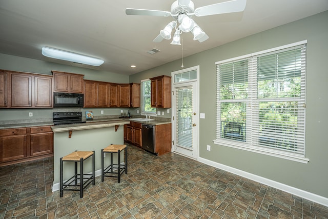 kitchen featuring a wealth of natural light, sink, a breakfast bar area, a kitchen island, and black appliances