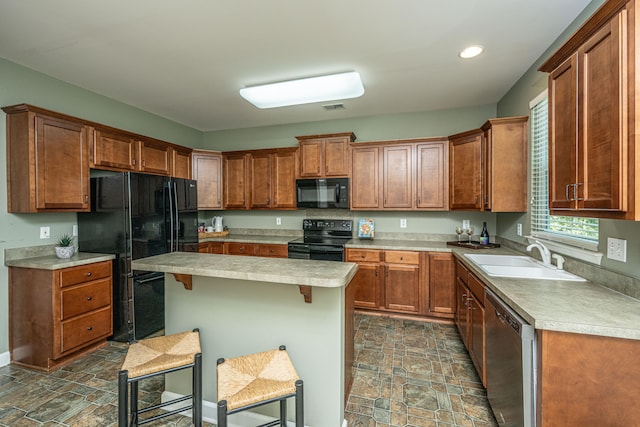 kitchen featuring black appliances, a kitchen island, a kitchen bar, and sink