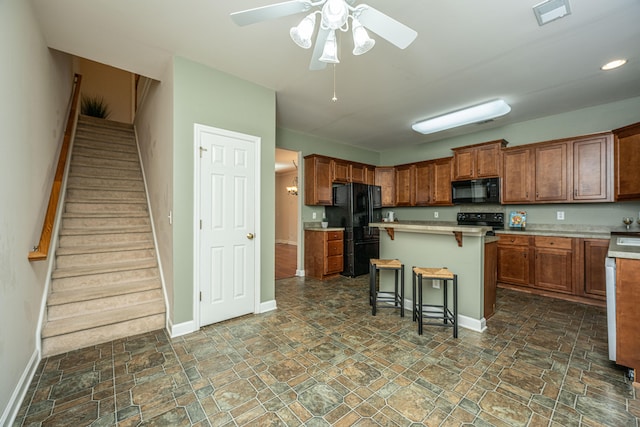 kitchen with black appliances, ceiling fan, a center island, and a kitchen bar