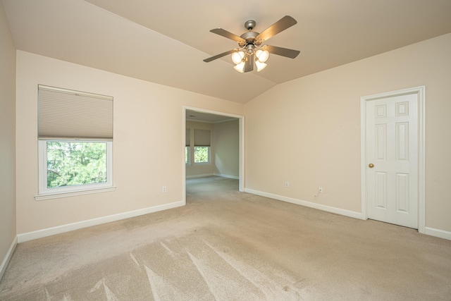 spare room featuring ceiling fan, light colored carpet, and lofted ceiling