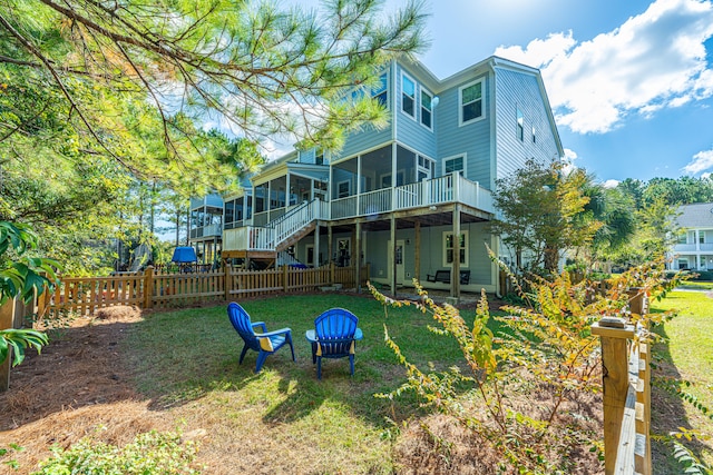 rear view of house with a yard, a deck, and a sunroom