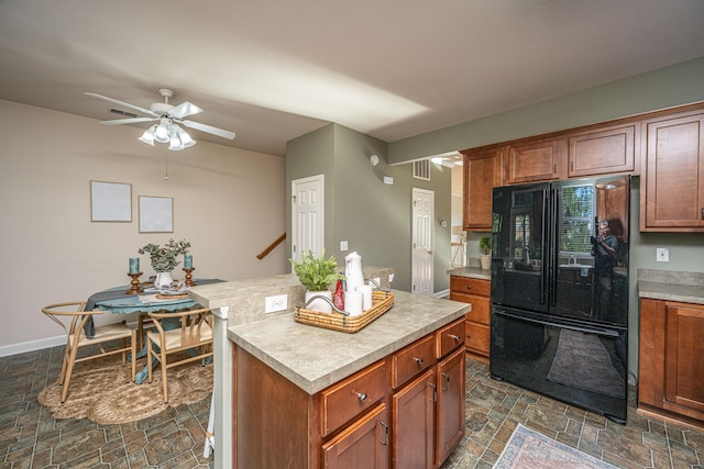 kitchen with black refrigerator, a center island, and ceiling fan