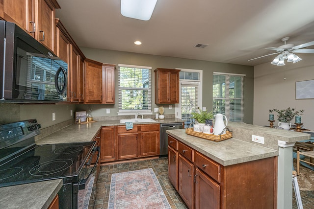 kitchen with ceiling fan, sink, a breakfast bar area, a kitchen island, and black appliances