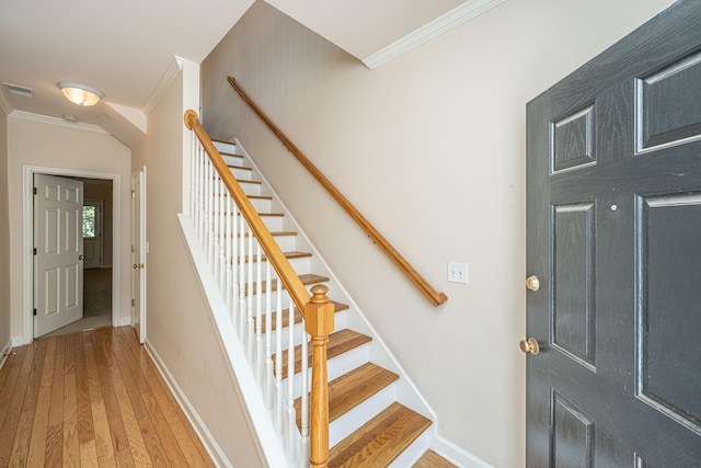 stairs with wood-type flooring and ornamental molding