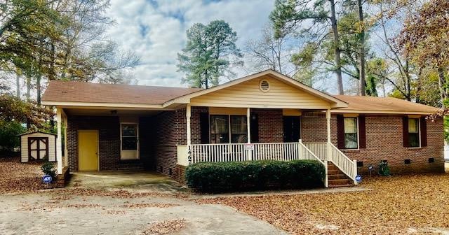 ranch-style house featuring a storage unit and covered porch