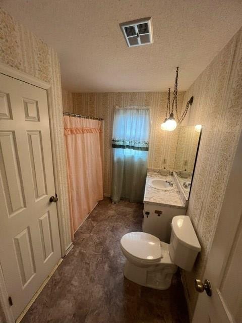 bathroom with a shower with curtain, vanity, toilet, and a textured ceiling