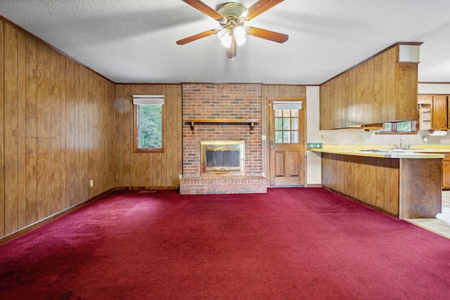 unfurnished living room featuring plenty of natural light, a textured ceiling, wood walls, and a fireplace