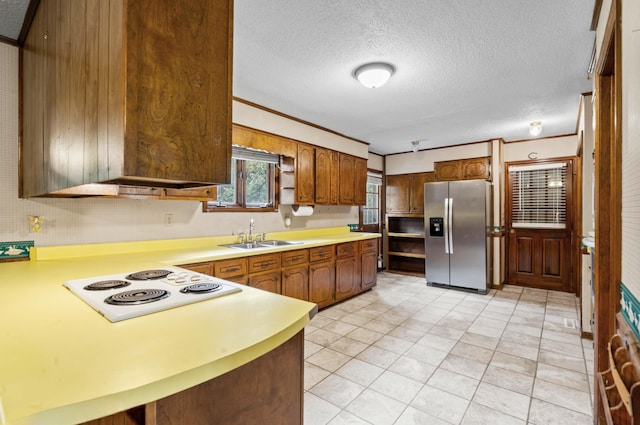 kitchen with sink, white electric stovetop, crown molding, and stainless steel fridge