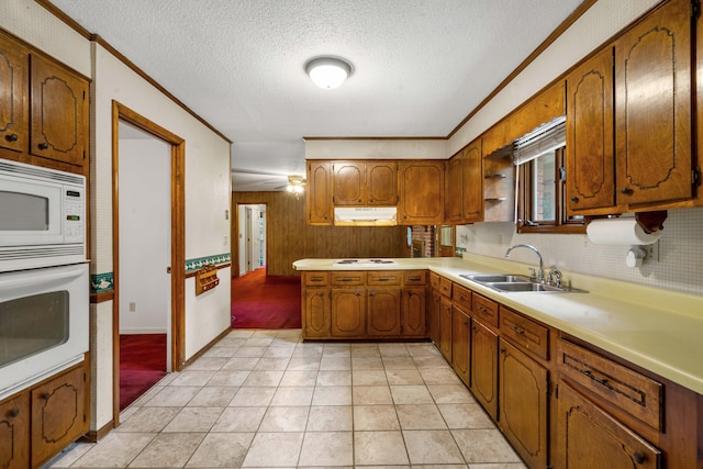 kitchen with sink, white appliances, a textured ceiling, and ornamental molding