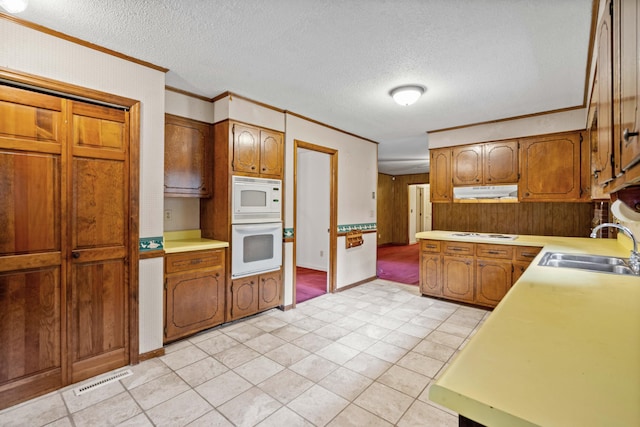 kitchen featuring sink, white appliances, ornamental molding, and a textured ceiling