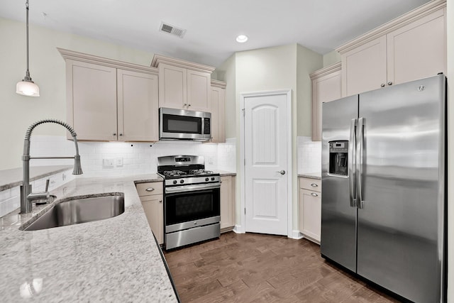 kitchen featuring pendant lighting, a sink, appliances with stainless steel finishes, visible vents, and dark wood finished floors