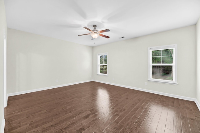 spare room featuring dark wood finished floors, baseboards, visible vents, and ceiling fan