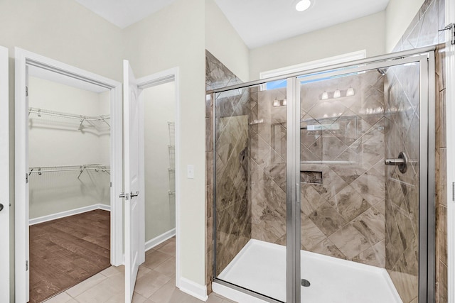 full bathroom featuring a shower stall, tile patterned floors, and a spacious closet