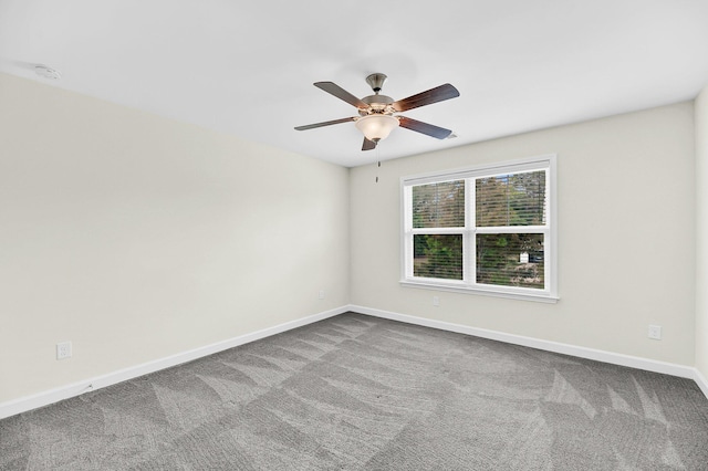 carpeted spare room with a ceiling fan and baseboards