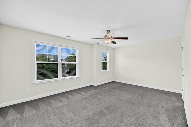 empty room featuring a wealth of natural light, dark carpet, and a ceiling fan