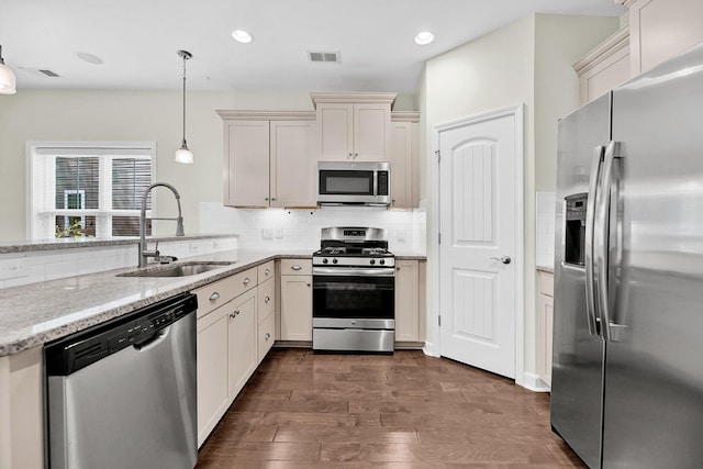 kitchen with stainless steel appliances, decorative light fixtures, backsplash, a sink, and visible vents