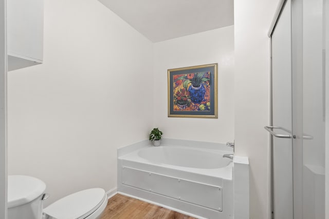 bathroom featuring hardwood / wood-style floors, toilet, and a tub to relax in