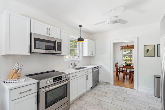 kitchen with light countertops, stainless steel appliances, white cabinets, and a sink