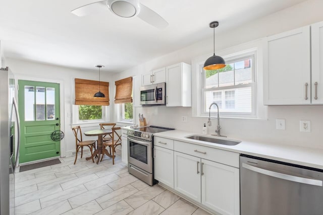 kitchen with a sink, light countertops, marble finish floor, stainless steel appliances, and white cabinetry