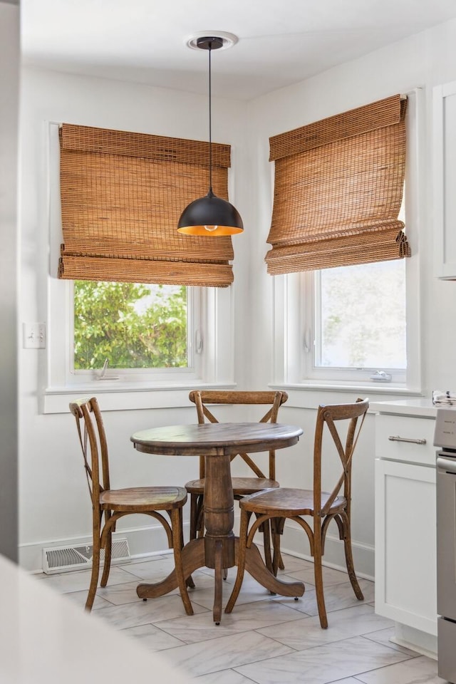 dining space with baseboards, visible vents, and plenty of natural light