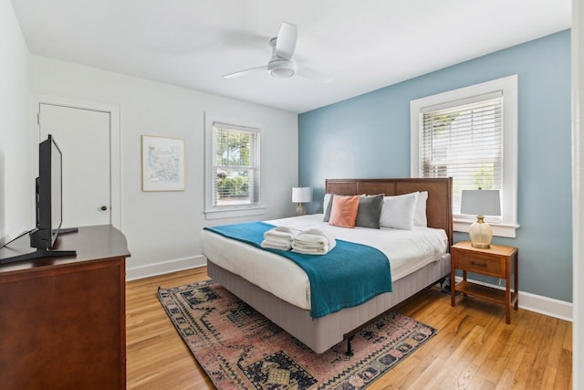 bedroom with baseboards, multiple windows, and light wood-type flooring