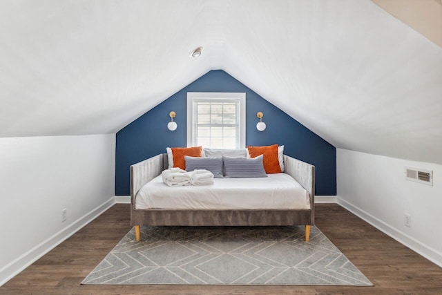 bedroom featuring visible vents, baseboards, lofted ceiling, and wood finished floors