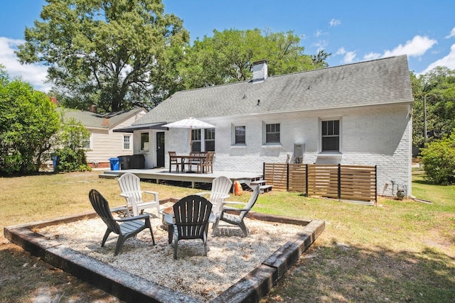 rear view of house with brick siding, a fire pit, and a yard