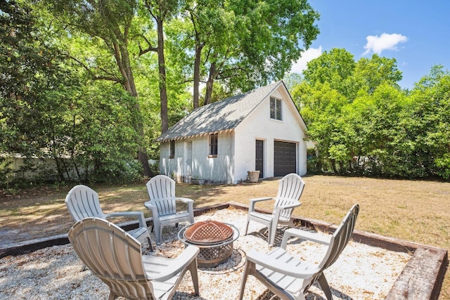 view of patio featuring an outdoor structure, a fire pit, and a detached garage
