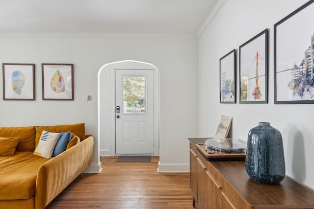 foyer entrance featuring baseboards, ornamental molding, and light wood-style flooring