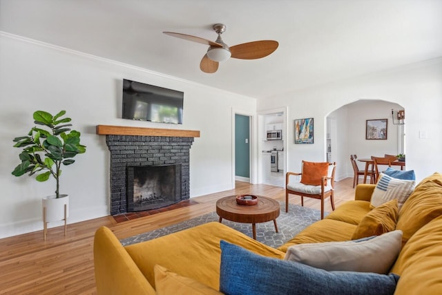 living area featuring crown molding, arched walkways, ceiling fan, and wood finished floors