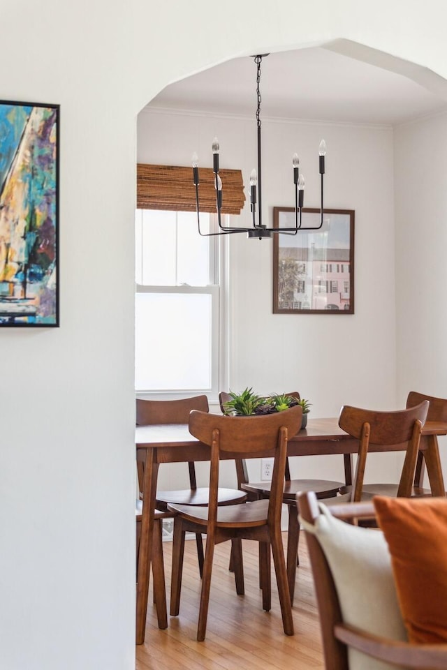 dining area featuring light wood-style floors, ornamental molding, and a notable chandelier