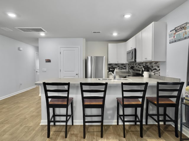 386 Spruce Ivy St, Moncks Corner, SC 29461 - kitchen with appliances with stainless steel finishes, a peninsula, light countertops, decorative backsplash, and white cabinetry