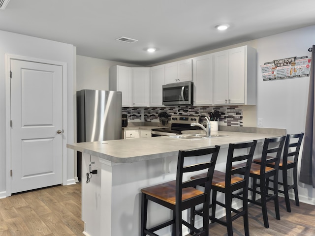 386 Spruce Ivy St, Moncks Corner, SC 29461 - kitchen with appliances with stainless steel finishes, a peninsula, light countertops, light wood finished floors, and backsplash