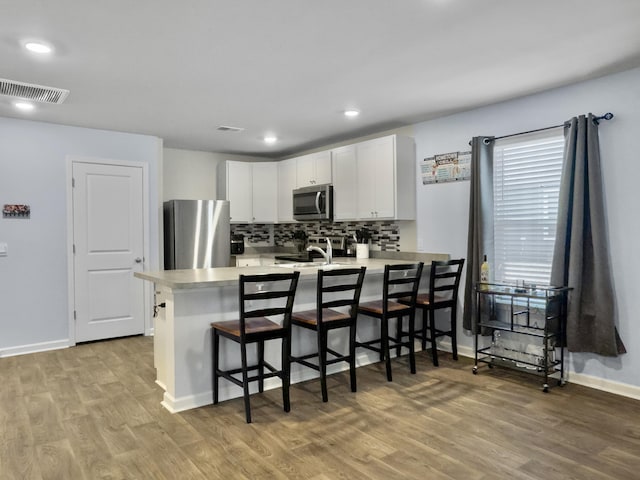 386 Spruce Ivy St, Moncks Corner, SC 29461 - kitchen with stainless steel appliances, light countertops, light wood finished floors, a breakfast bar area, and recessed lighting