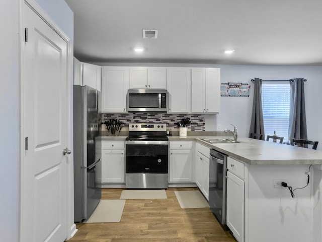 386 Spruce Ivy St, Moncks Corner, SC 29461 - kitchen with stainless steel appliances, a peninsula, tasteful backsplash, white cabinetry, and light wood-style flooring