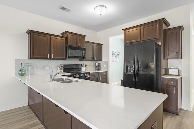 kitchen featuring dark brown cabinetry, visible vents, light wood-style flooring, black appliances, and a sink