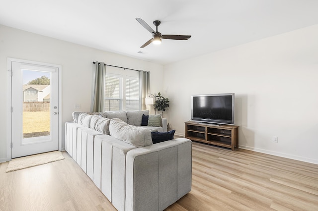 living area with light wood-style floors, ceiling fan, and baseboards