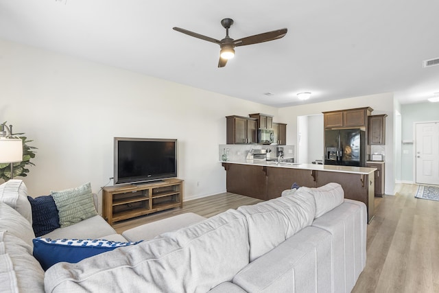 living room with light wood finished floors, baseboards, visible vents, and a ceiling fan